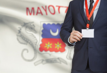 Businessman holding name card badge on a lanyard with a national flag on background - Mayotte
