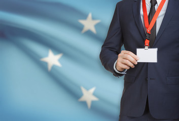 Businessman holding name card badge on a lanyard with a national flag on background - Micronesia
