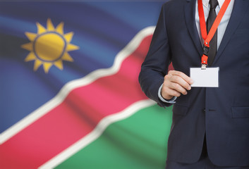 Businessman holding name card badge on a lanyard with a national flag on background - Namibia