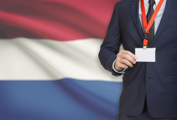 Businessman holding name card badge on a lanyard with a national flag on background - Netherlands