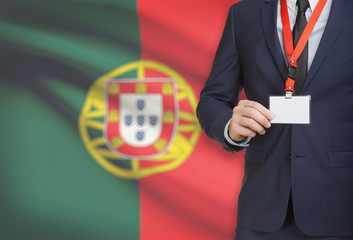 Businessman holding name card badge on a lanyard with a national flag on background - Portugal