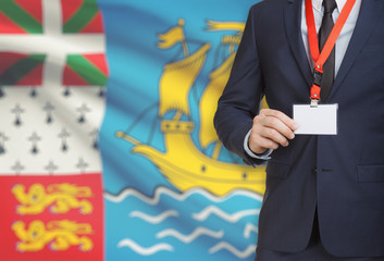 Businessman holding name card badge on a lanyard with a national flag on background - Saint Pierre...