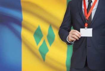 Businessman holding name card badge on a lanyard with a national flag on background - Saint Vincent...
