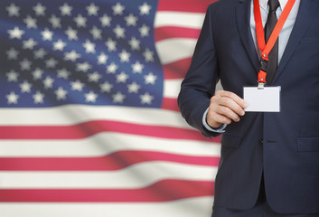Businessman holding name card badge on a lanyard with a national flag on background - United States