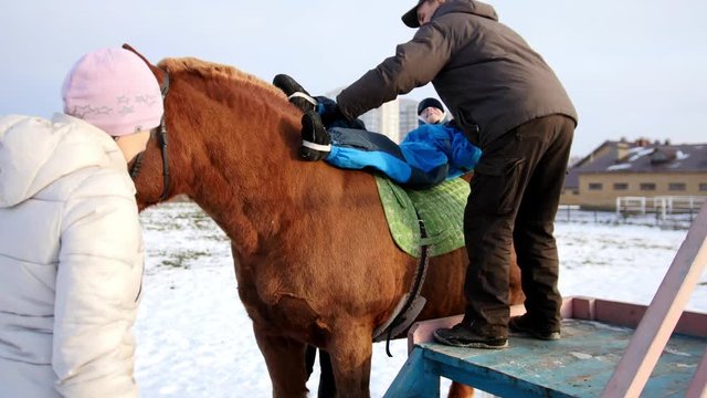 Contact kids therapy and rehabilitation horseriding club - adult man with kids with cerebral palsy syndrome learn to ride a horse back and play with horses
