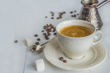 Coffee composition with beautiful white cup of coffee, coffee grinder on white wooden background