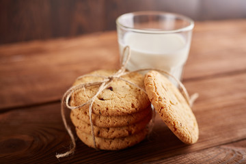 Fototapeta na wymiar Cookies and milk. Chocolate chip cookies and a glass of milk. Vintage look. Tasty cookies and glass of milk on rustic wooden background. Food, junk-food, culinary, baking and eating concept