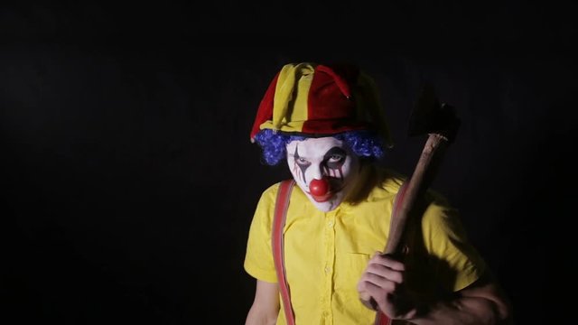 Terrifying clown with an axe frightening you. HD.