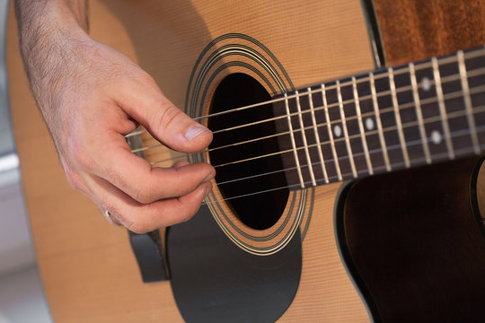 Man's hand playing acoustic guitar