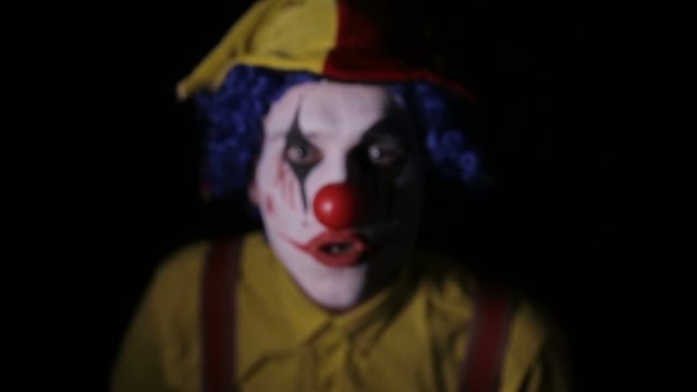 The scary clown making horror faces into camera. Halloween horror clowns. HD.