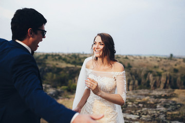 beautiful and happy groom and bride walking outdoors