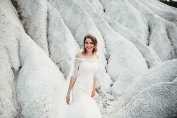 beautiful bride in a white dress stands outdoors