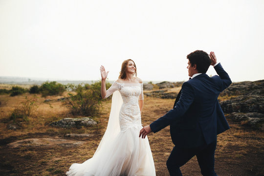 beautiful and happy groom and bride walking together outdoors