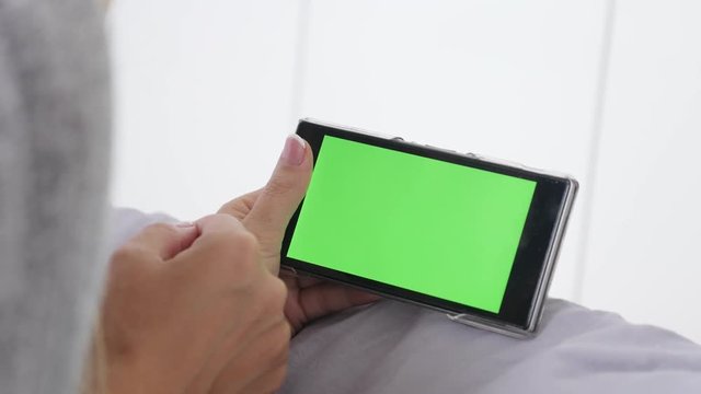 Woman at home using chroma key greenscreen smart phone 4K 2160p 30fps UltraHD footage - Relaxing in bed blond female surfing on green screen display tablet 3840X2160 UHD video 