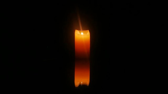 Burning candle reflected on the mirror surface