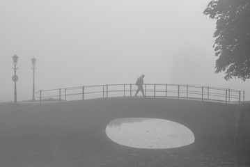 Lone hiker in the early foggy morning on fortified bridge in Elb