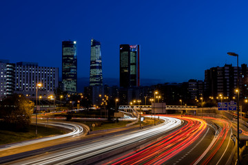 Obraz na płótnie Canvas Anochecer de Madrid con los rascacielos y las luces de la carretera