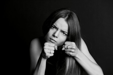 Hostile posture. Clenched fists before her face. Young beautiful girl with long hair