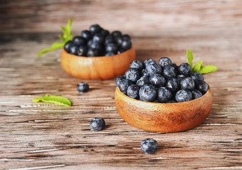 fresh bilberries or blueberries in small wooden bowls, selective focus