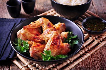 Grilled chicken wings with rice and chili sauce on the old wooden background.