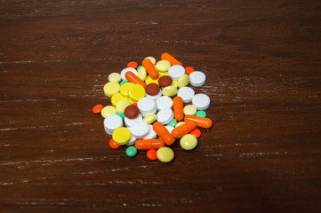 Colorful pills on wooden background.