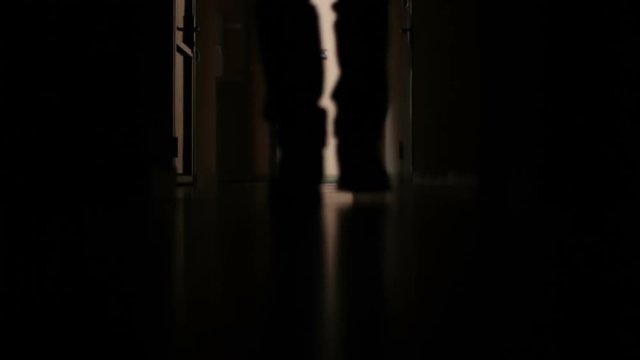 a man walks down the dark corridor