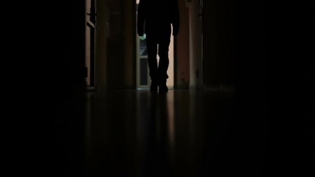 a man walks down the dark corridor