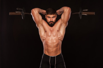 Muscular male athlete is training by lifting the barbell
