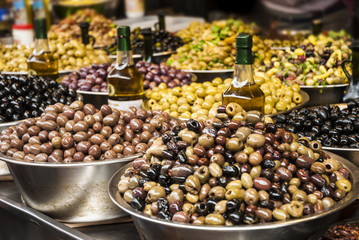 Olives at a market stall. Countertop with different pickling olives on the market.  Green, black and others.(selective focus)