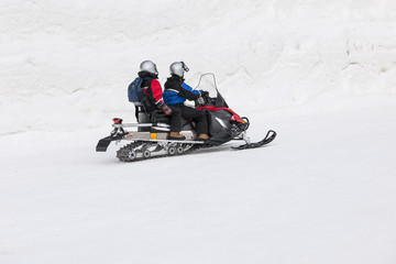 Fototapeta na wymiar Couple driving snowmobile in snowy field