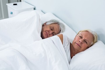 Side view of senior couple sleeping on bed 