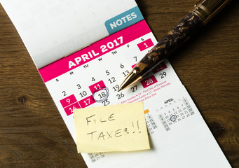 Gold pen laying on calendar for tax day