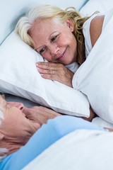 Cheerful senior couple sleeping on bed