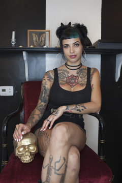 Portrait of young woman sitting with a gold skull in salon