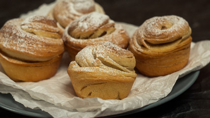 Obraz na płótnie Canvas Homemade pastries cruffins, muffin with sugar powder, on dark background, selective focuse close up