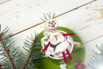 Christmas card with fun marshmallow snowman in green cup, tree