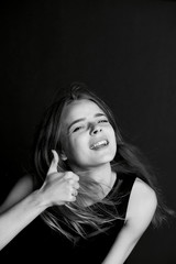 Young beautiful girl with long hair in Studio. Gesture thumb up with a smile. BW