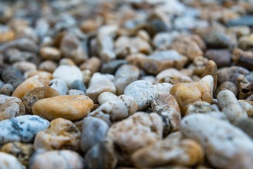 Background of colorful beach pebbles of different shape and size. Shallow DOF. Selective focus.