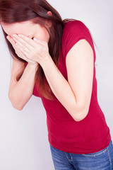 Young woman crying, covering her face with her hands