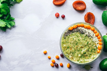 green smoothie with sea buckthorn, Chia seeds and sesame seeds on a white table surrounded by feijoas, apricots, cherries, parsley, Kalina. healthy vegan and vegetarian food. Copy space
