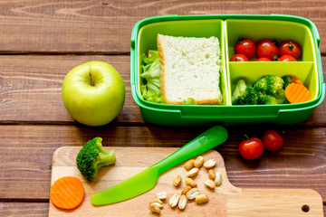 lunch box for kid with fresh vegetables on wooden background