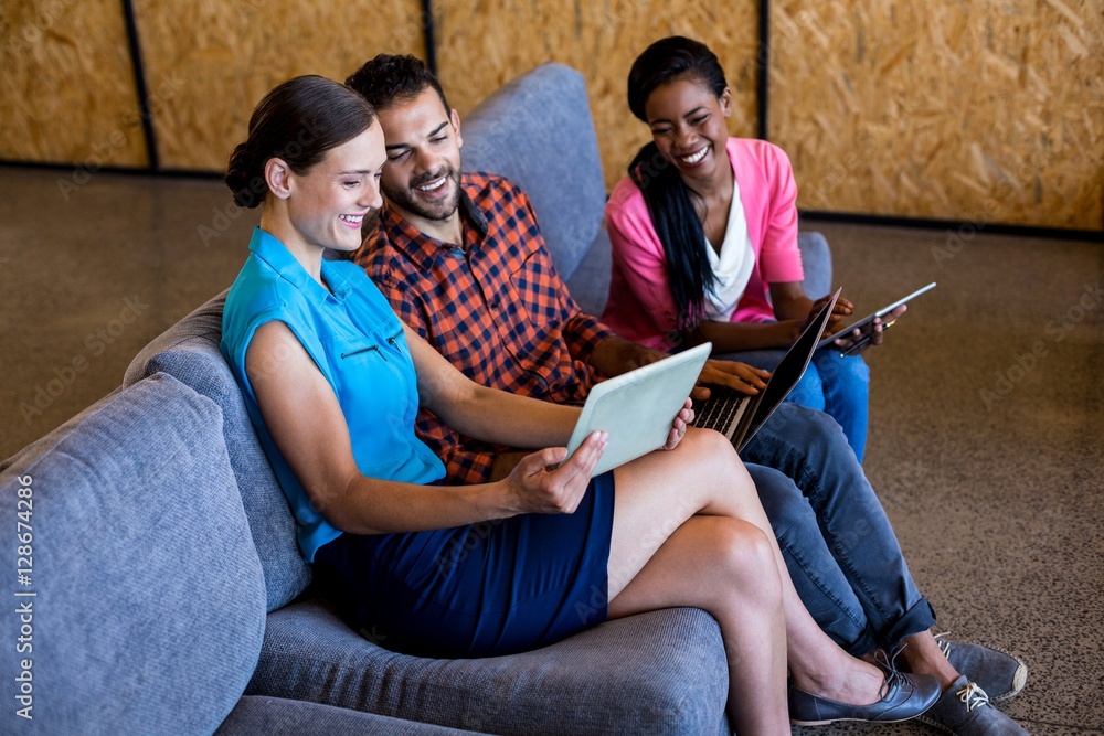 Aufkleber colleagues using digital tablet and laptop while sitting on sofa