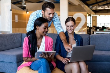 Colleagues interacting using digital tablet and laptop