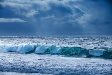 storm surf and rain clouds with rays of sunlight 