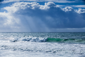 storm surf and rain clouds with rays of sunlight 
