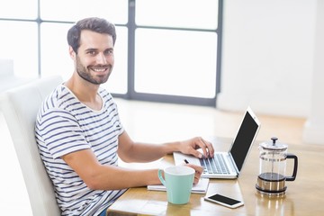 Man smiling at camera while writing notes