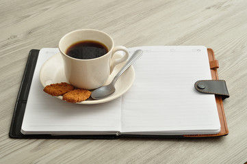 Fototapeta na wymiar A mug of coffee, biscuits and a notebook