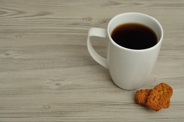 A white mug with coffee and golden square biscuits