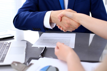 Businessman and business woman shaking hands to each other above signed contract