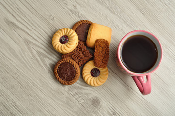 A pile of biscuits with a pink mug filled with coffee. Top view.